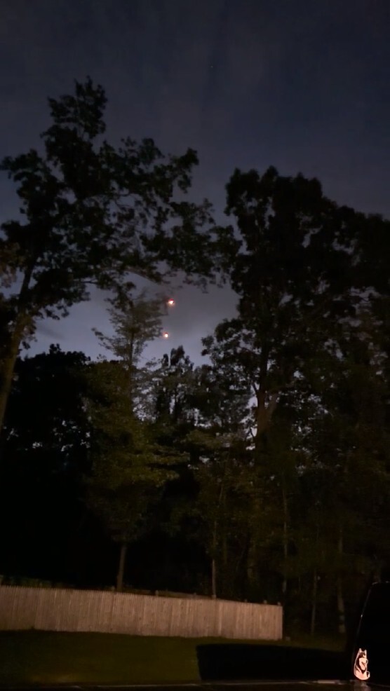 A still image extracted from a video featuring two lights above a treeline.
